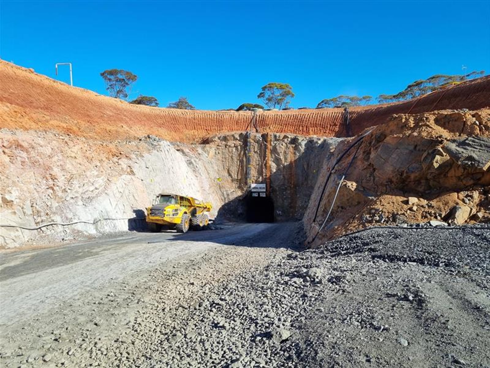 A decline portal cut into a hillside with a haul truck at the entrance